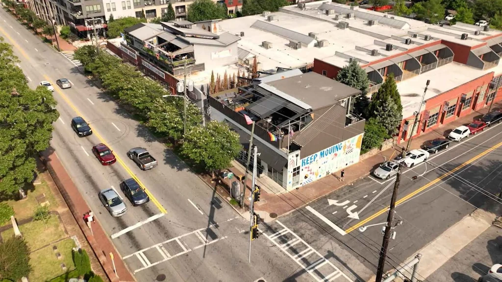 Aerial view of a city street with "KEEP MOVING" mural, rainbow flags.