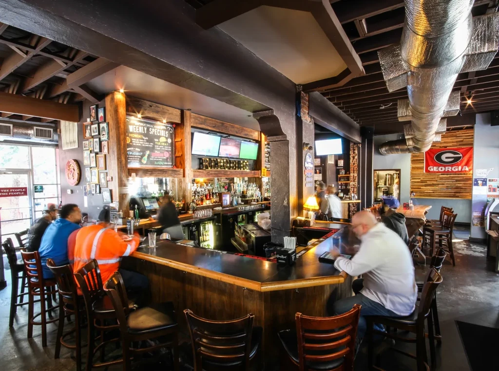 Patrons at a long dark wood bar in a casual pub.