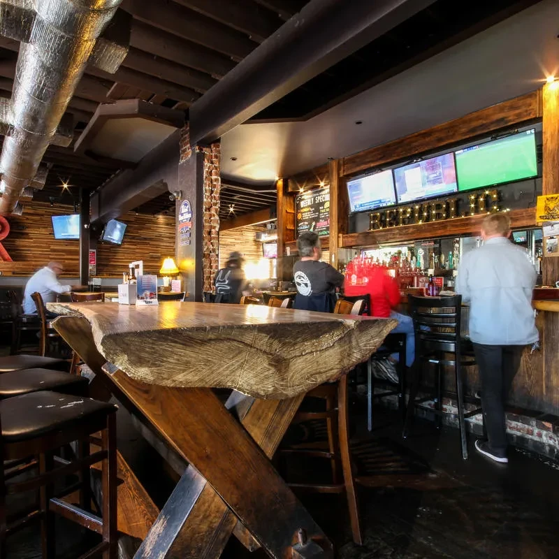 Rustic industrial bar interior with live-edge communal table and beer taps.