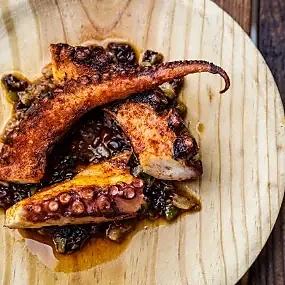 Grilled octopus with potatoes served on a round wooden board