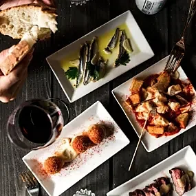 Spread of tapas plates with bread and glass of red wine