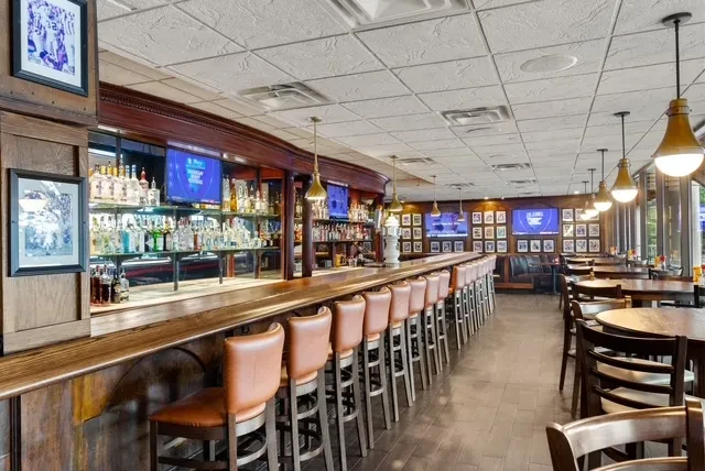 Empty, spacious bar and restaurant interior with a long wooden bar.