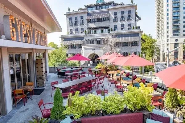 Outdoor restaurant patio with red chairs, umbrellas, and "GYPSY KITCHEN" sign.
