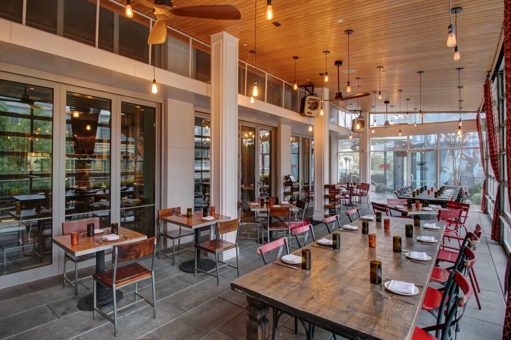Spacious modern restaurant with high wooden ceiling, Edison bulbs, and varied seating.