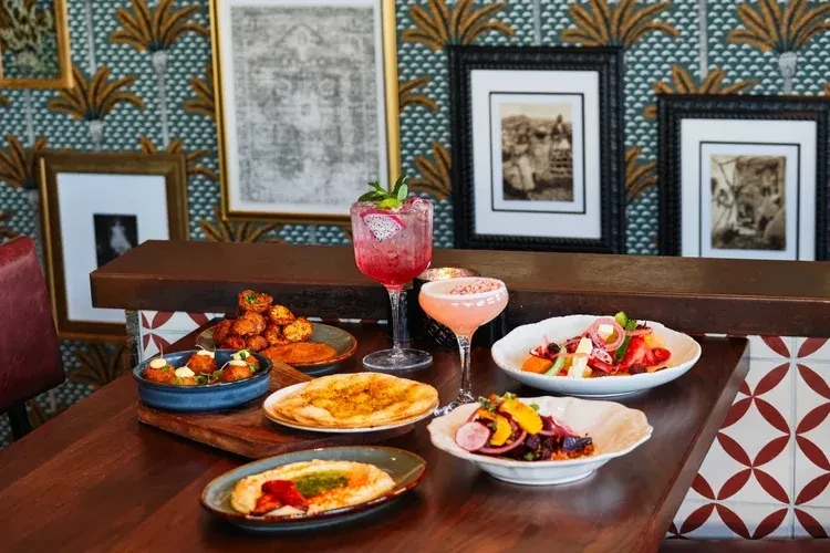 Colorful dishes and garnished cocktails on a table in a stylish restaurant.