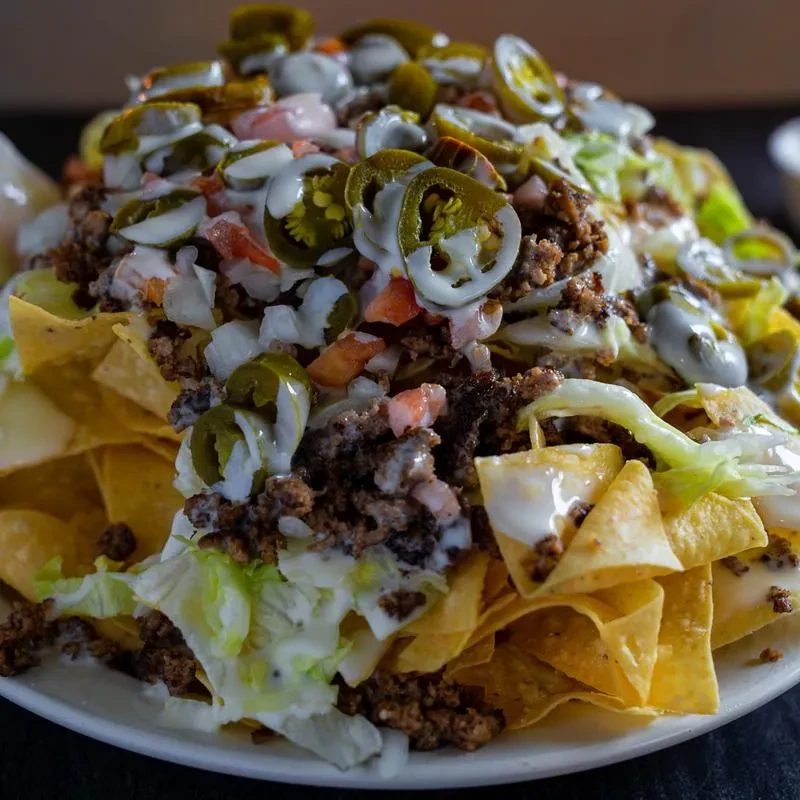 Loaded nachos with seasoned meat, pico de gallo, jalapeños, and creamy sauce.