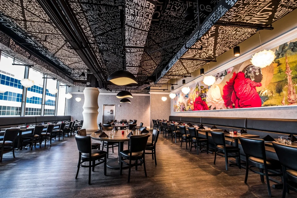 Empty modern restaurant interior featuring artistic ceiling and colorful mural.