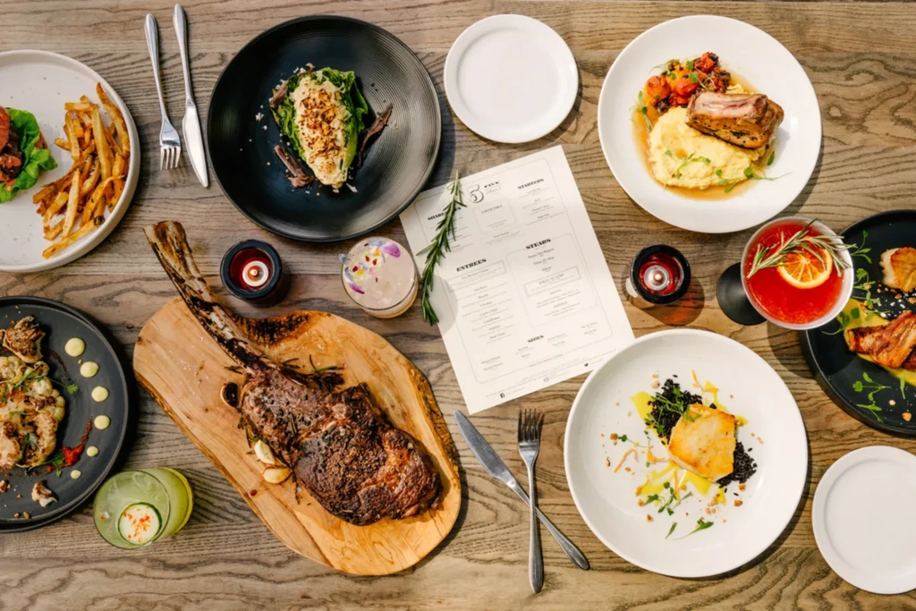 Overhead view of a lavish gourmet meal and cocktails on an upscale table.