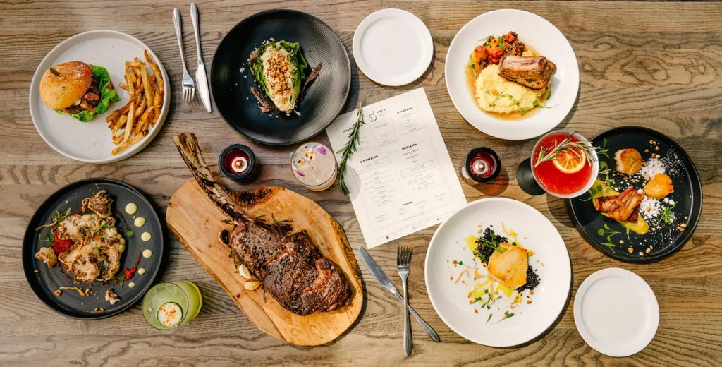 Overhead view of a dining table with artfully presented dishes and cocktails.
