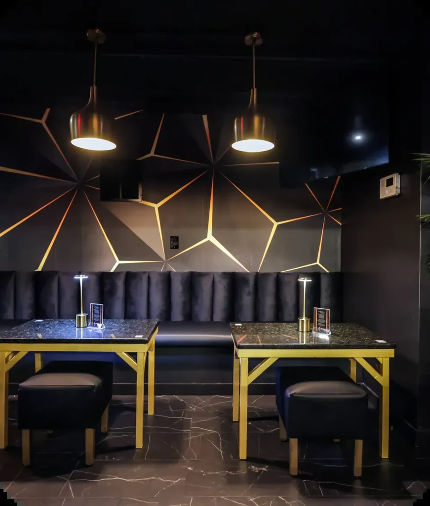 Modern black and gold restaurant seating with geometric wall pattern.