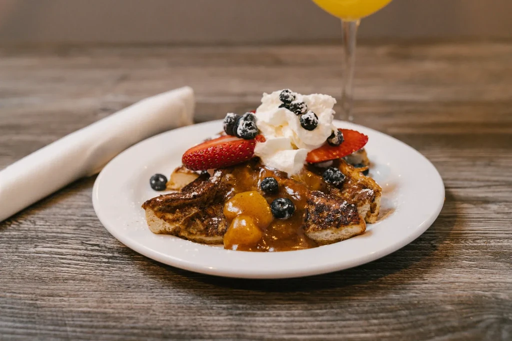 French toast with peach compote, whipped cream, berries, powdered sugar.