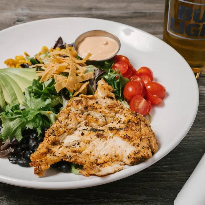 Grilled chicken salad with avocado, corn, black beans, and a Bud Light.