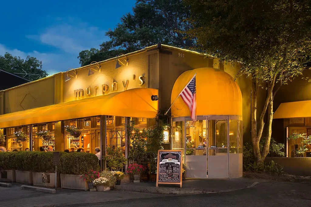 Murphy's restaurant exterior at dusk with golden awnings and flag.