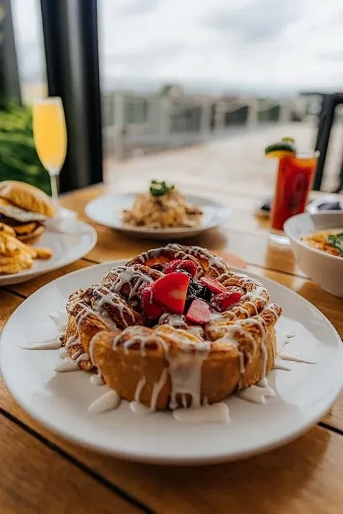 Large pastry with icing and fresh berries on a restaurant table.