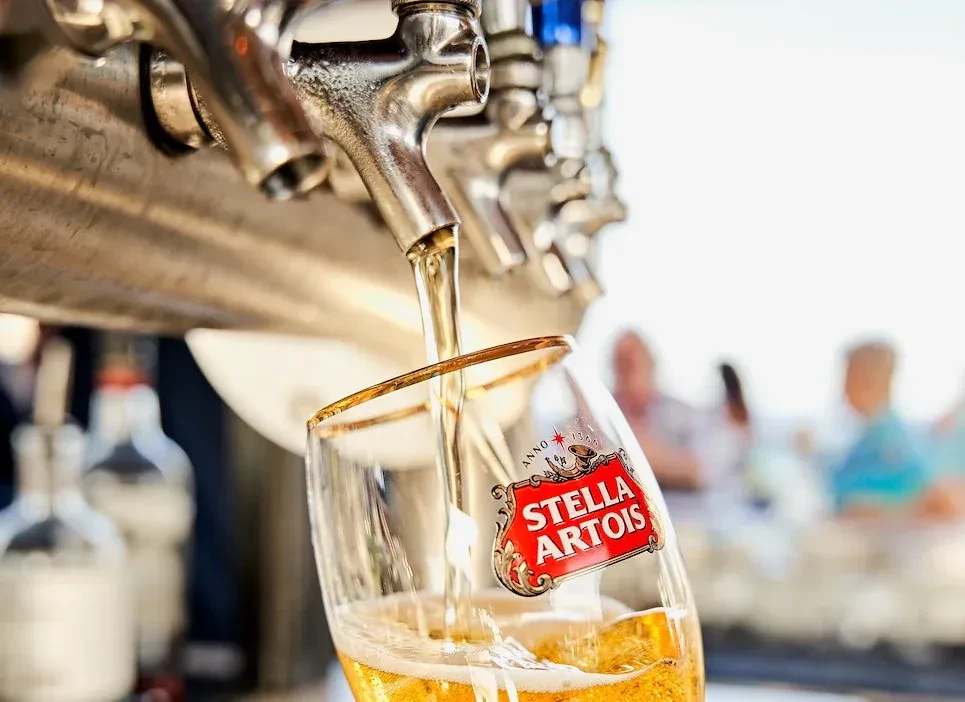 Golden Stella Artois beer fills a branded glass from a tap.