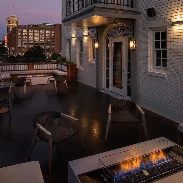 Empty outdoor patio with a fire pit, cityscape, and twilight sky.