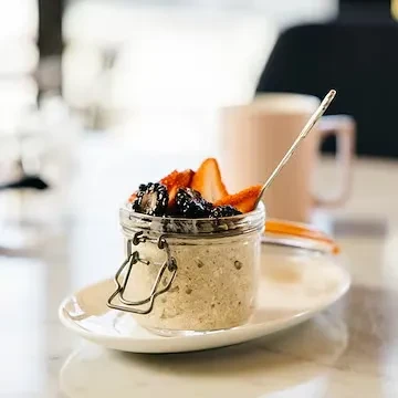 Glass jar of overnight oats with strawberries, blackberries, and a spoon.