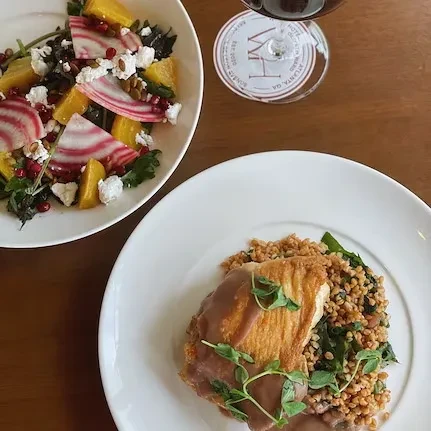 Salad with beets, protein dish, red wine on wooden table.