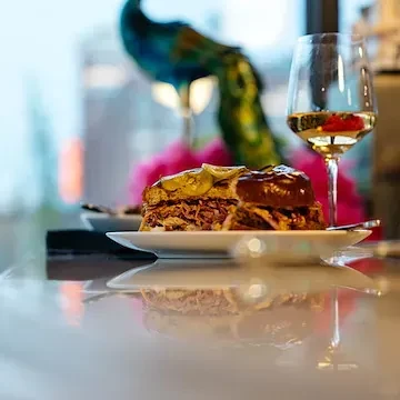 Plate of pulled pork, pickles, dark sauce, and white wine.