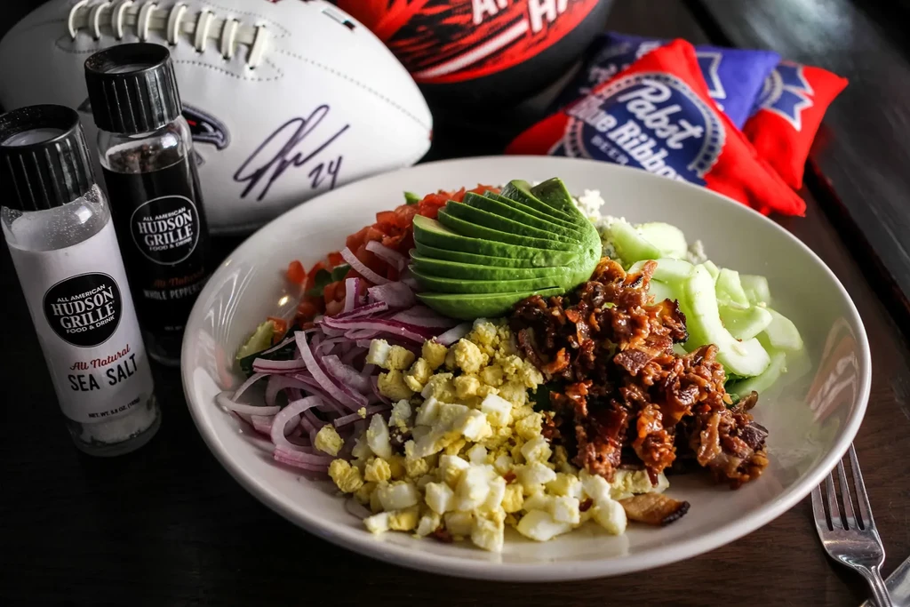 Colorful deconstructed salad in a bowl, with sports decor background.