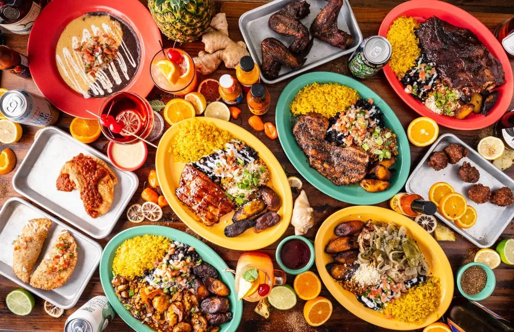 Overhead shot of a table abundant with Caribbean food, drinks, and fruit.