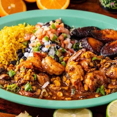 Plate of yellow rice, black beans, fried plantains, and shrimp stew.
