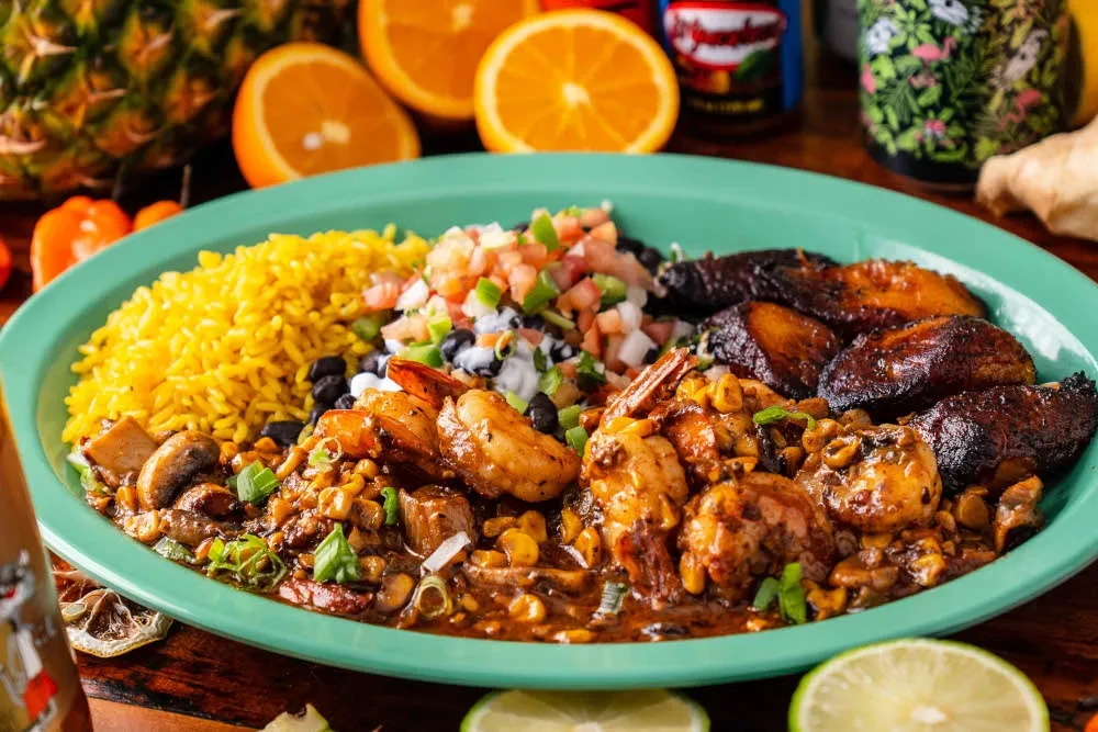 Teal dish with yellow rice, shrimp, pico de gallo, black beans, plantains.