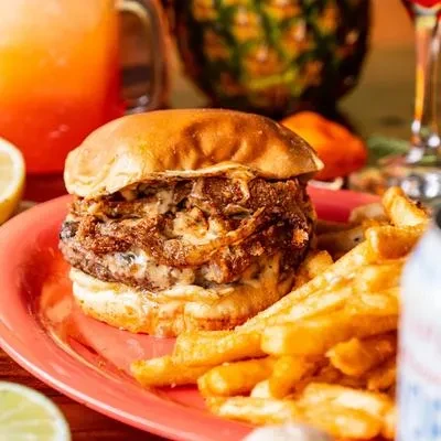 Close-up of a burger with onions, cheese, and golden french fries.