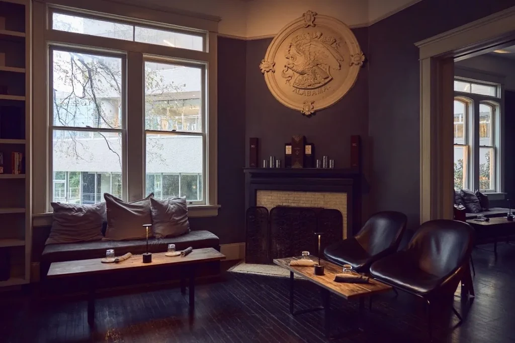 Sophisticated lounge with Alabama eagle crest art, dark decor, and window seating.