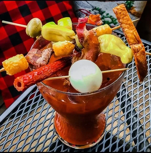 Extravagantly garnished Bloody Mary-style cocktail with meat, fries, and pickles.