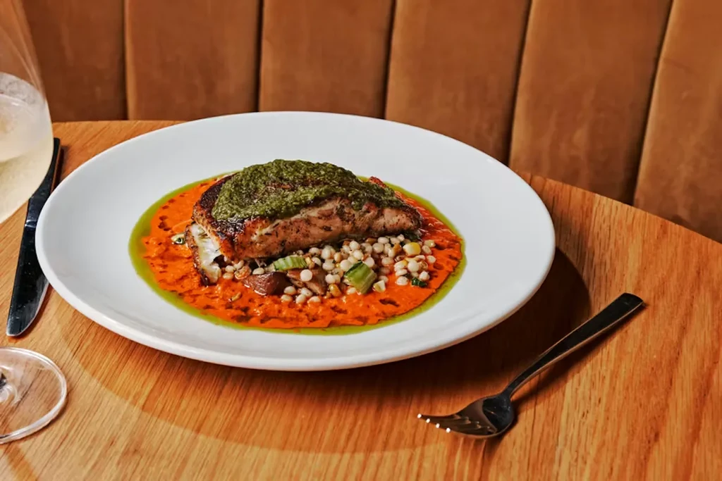 Pan-seared fish, green sauce, orange puree, Israeli couscous with vegetables.