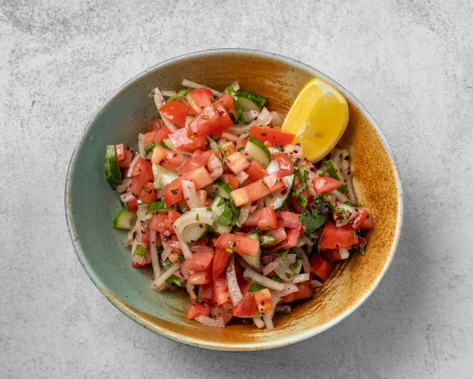 Fresh chopped salad with tomatoes, cucumbers, onions, herbs, and lemon.