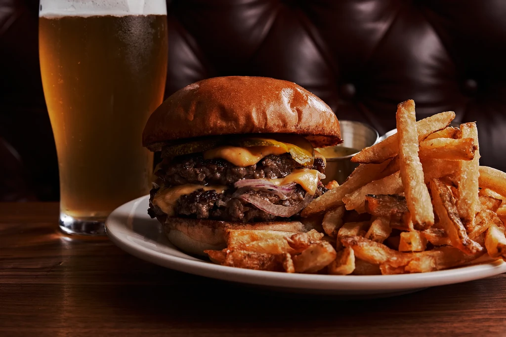 Gourmet double cheeseburger with melted cheese, fries, and beer.