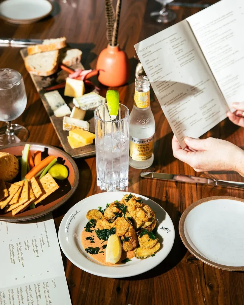 Overhead: wooden table with fried cauliflower, cheese, tonic water, menus.