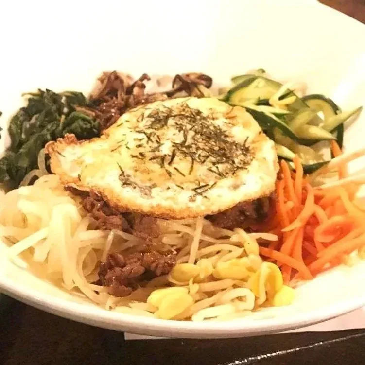 Korean Bibimbap bowl with fried egg, vegetables, and shredded beef.