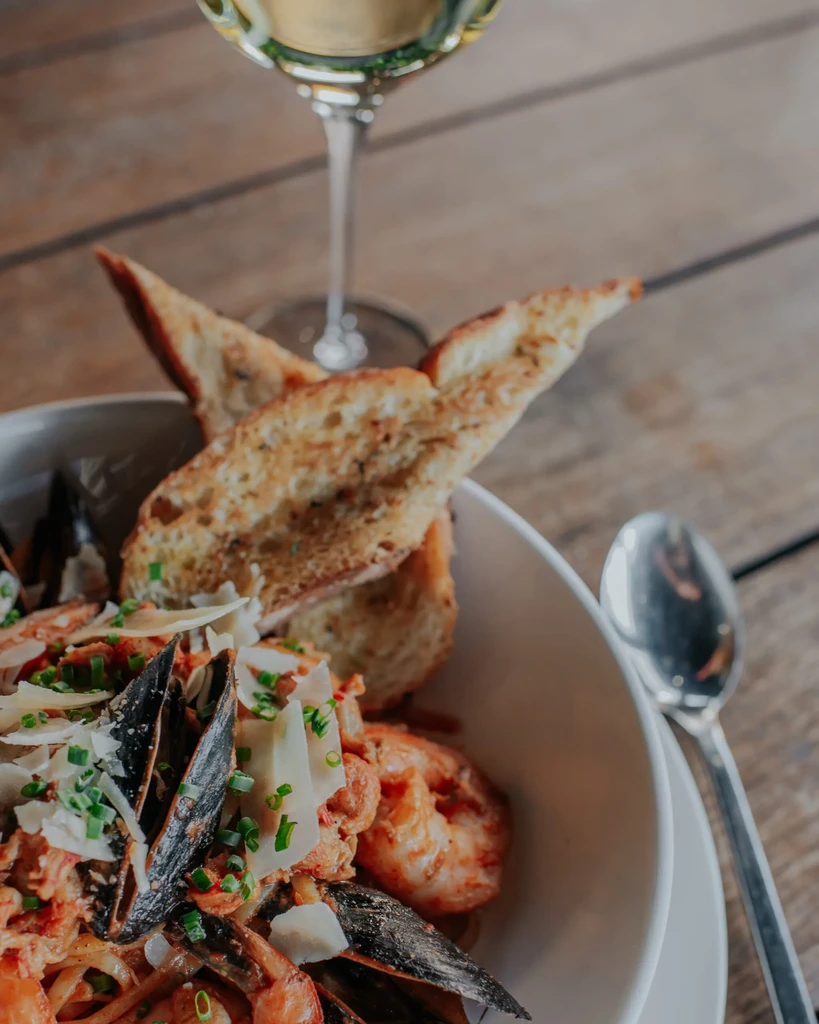 Seafood pasta with mussels, shrimp, garlic bread on a rustic table.