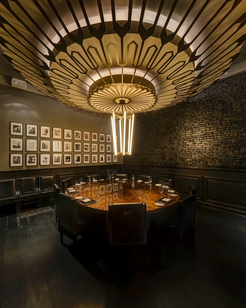 Dimly lit private dining room with an ornate ceiling and set table.