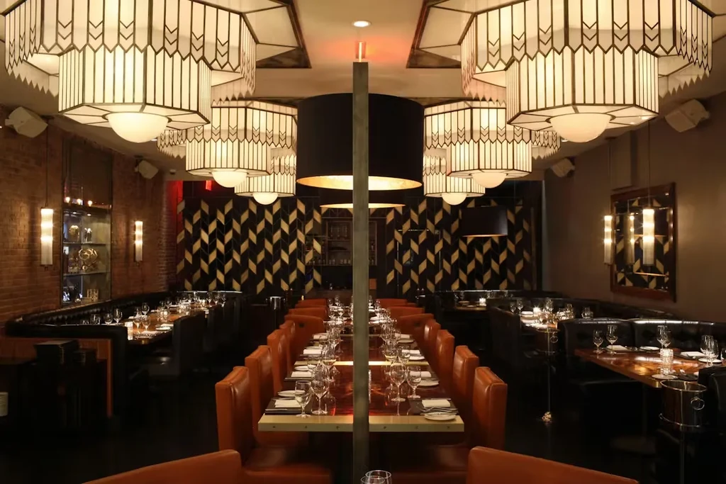 Upscale restaurant dining room featuring burnt orange booths and Art Deco chandeliers.