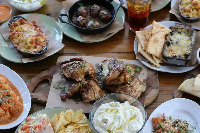 Overhead view: Wooden table with chicken, mac and cheese, and dips.