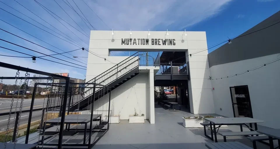 Modern Mutation Brewing building, patio with tables, swings, and lights.