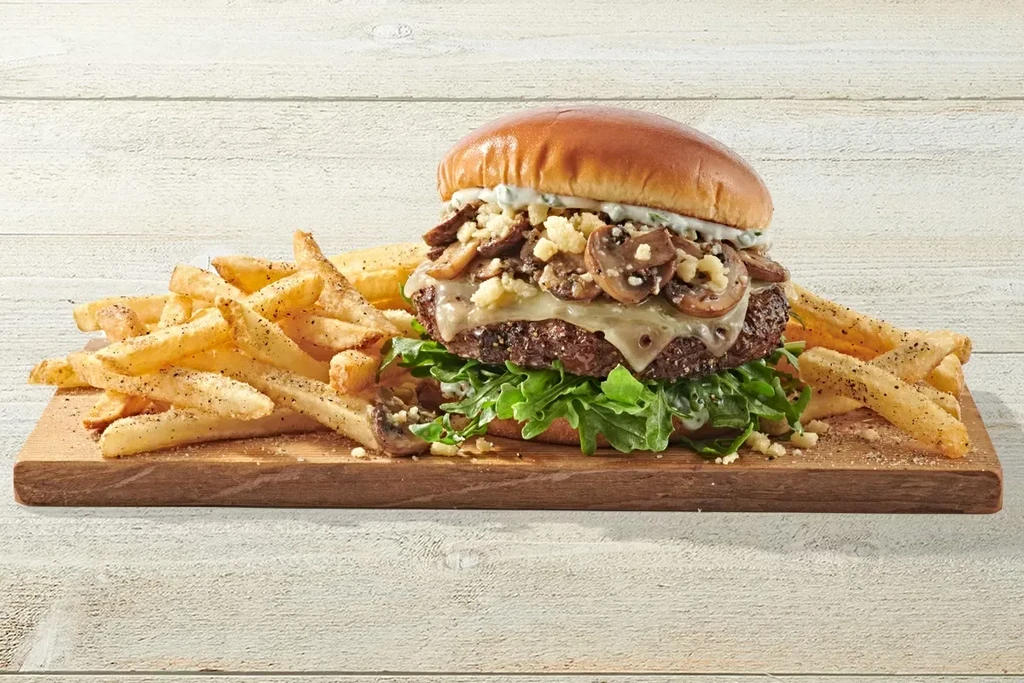 Thick beef brioche burger with cheese, mushrooms, arugula, and fries.