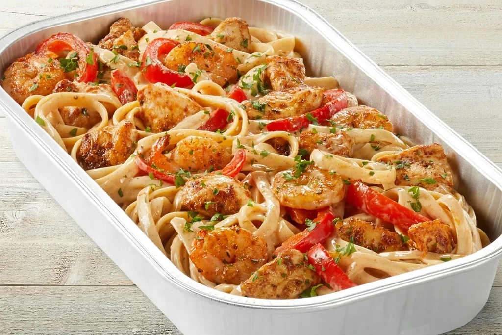 Creamy pasta with chicken, shrimp, bell peppers in a foil pan.