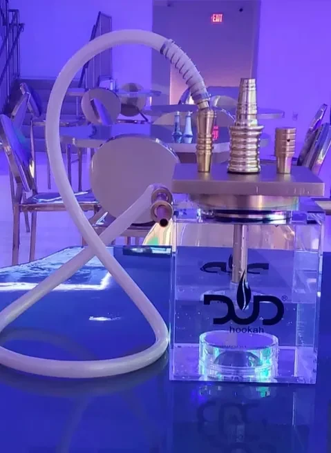 Modern DUD hookah, clear base, gold parts, in a blue-lit lounge.