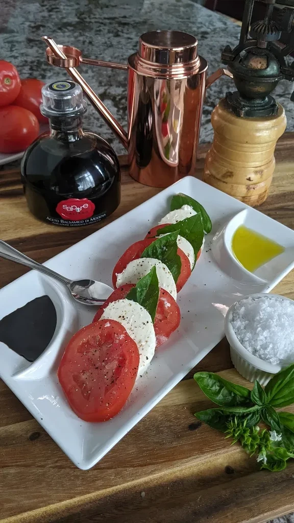 Fresh Caprese salad with tomatoes, mozzarella, basil, and dressings.