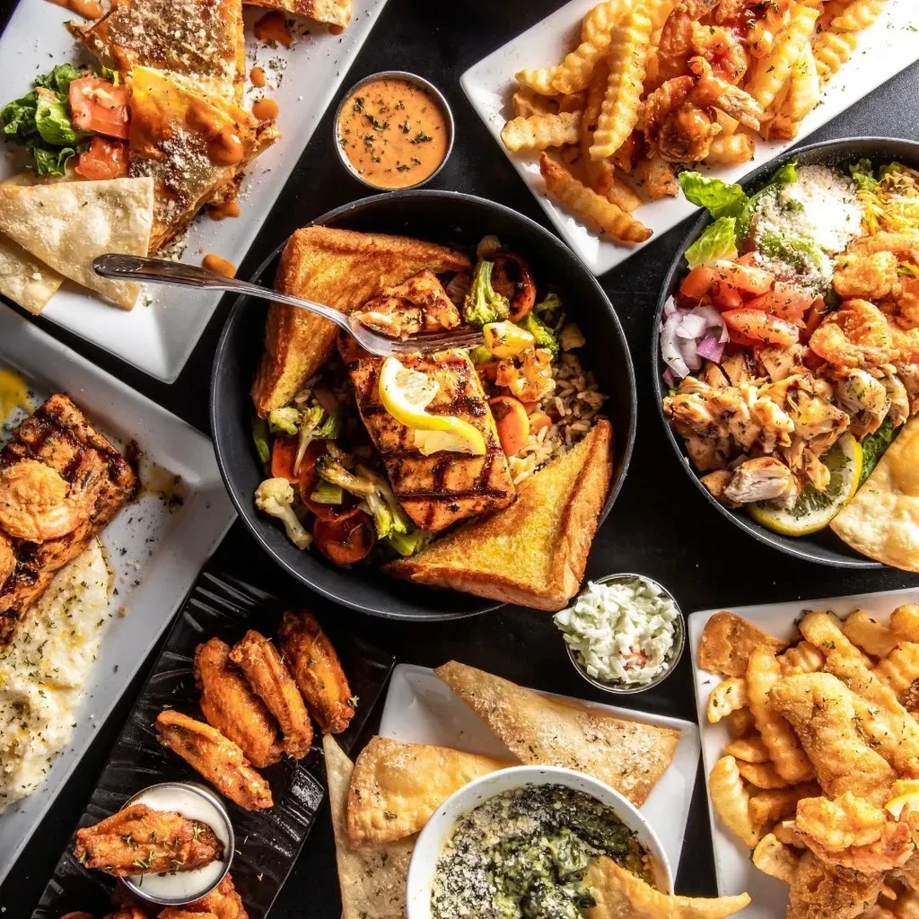 Diverse spread of grilled and fried food on a dark table.