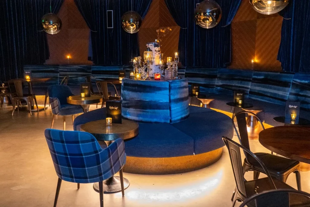 Elegant blue lounge interior with candlelit seating and accent lighting.