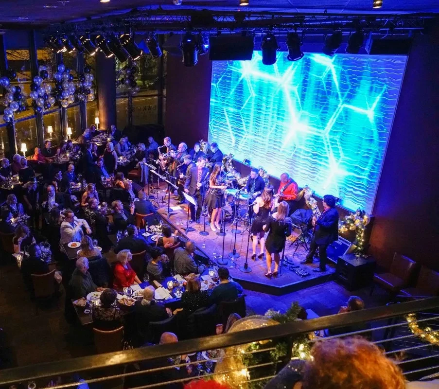 Vibrant restaurant with live band, abstract LED screen, and festive audience.