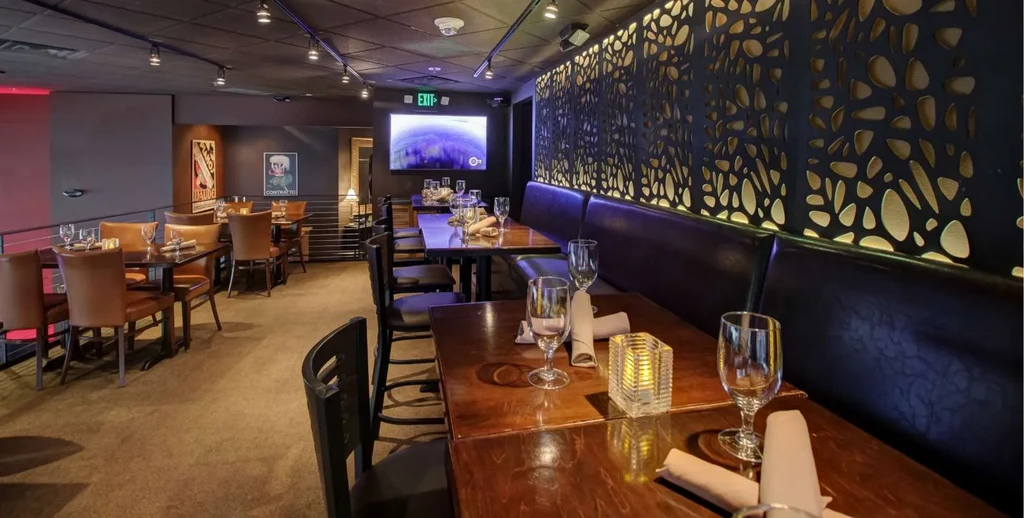 Empty, elegant restaurant interior with dark wood and backlit wall panels.