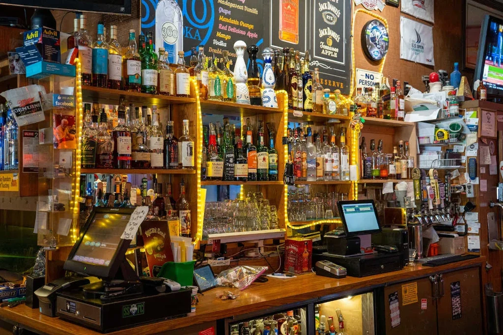 Vibrant bar interior with illuminated liquor shelves, POS, and counter.