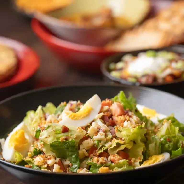 Fresh salad with lettuce, hard-boiled eggs, red onion, and topping.
